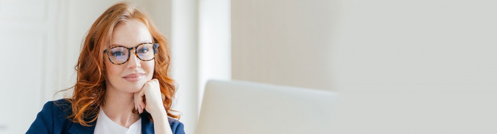 A woman reading a computer screen with pen in hand