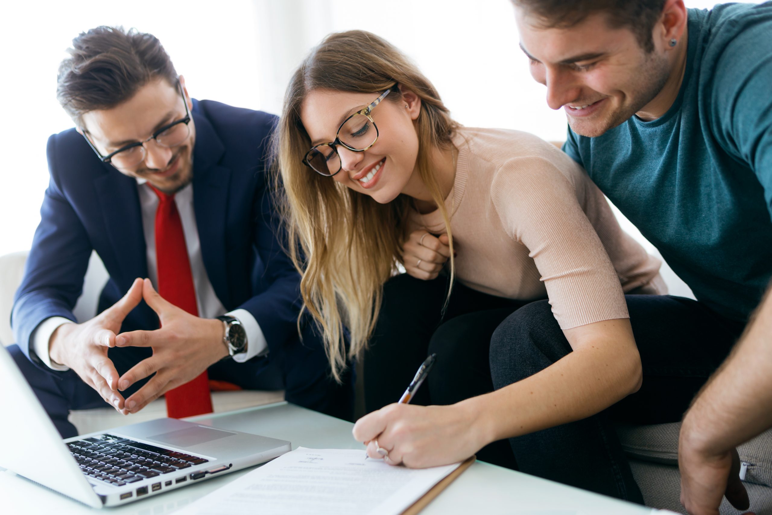 Portrait of young couple signing financial contract in the office.
